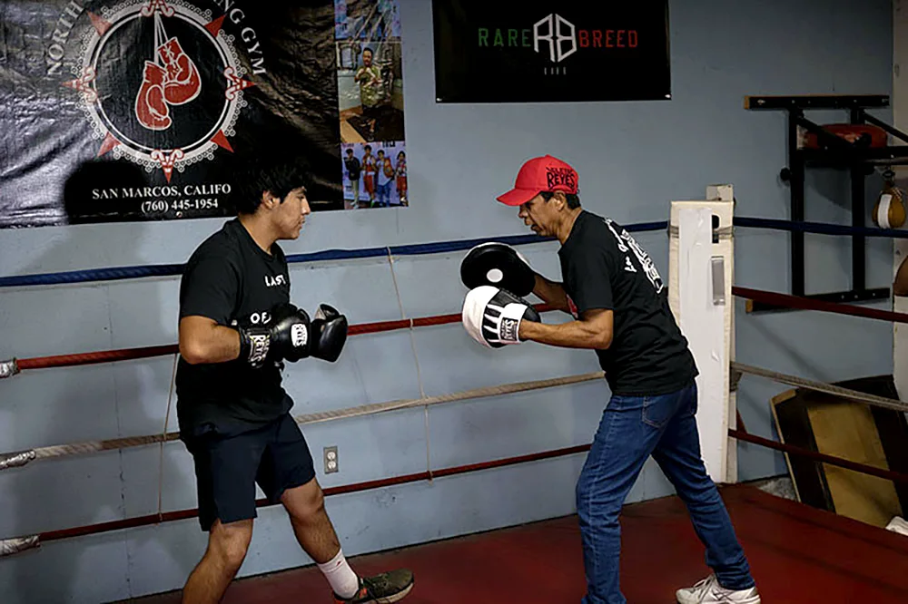 Manuel 'Mantecas' Medina doing some mitt work on the ring with one of the attendees at the event 'Espiritu de Campeón' in San Marcos, CA