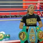 Urvashi Singh posing while proudly holding her champion belts