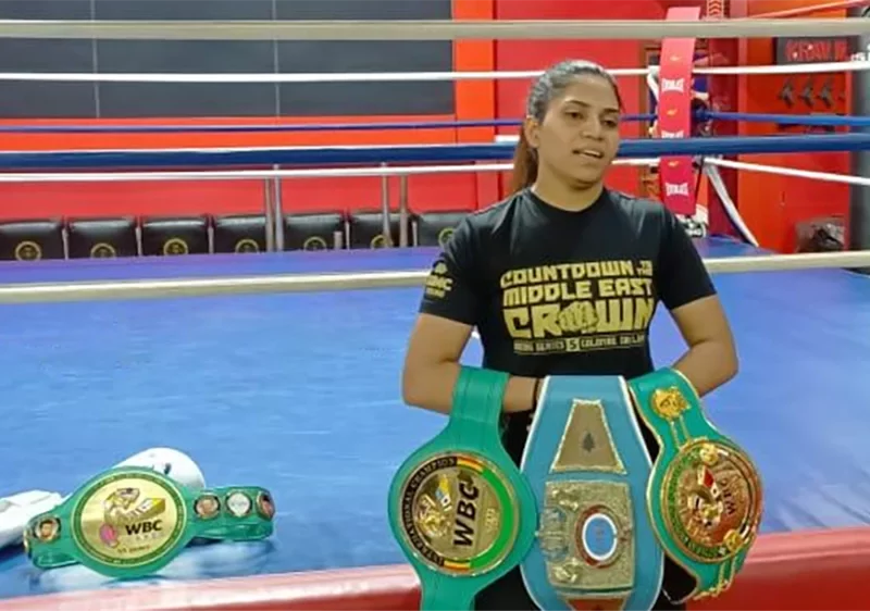 Urvashi Singh posing while proudly holding her champion belts
