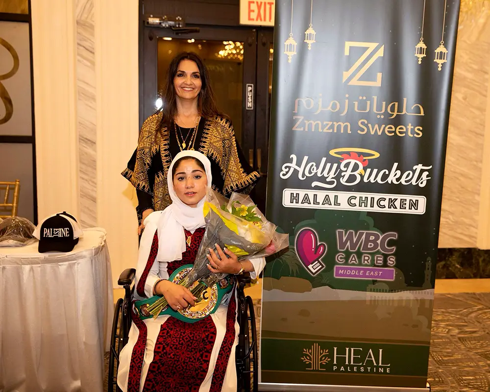 Photo of Leyan, (a resilient 14-year-old girl from Gaza who tragically lost both of her legs in a bombing), holding flowers and a WBC champion belt