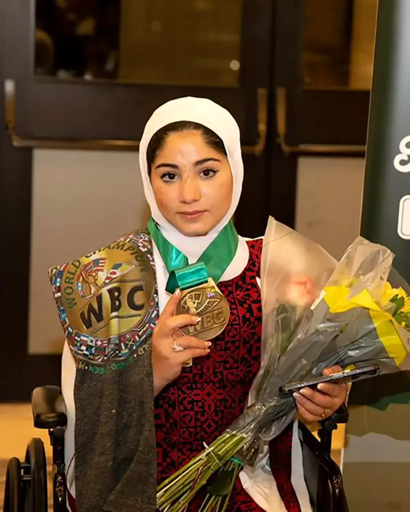 Photo of Leyan, (a resilient 14-year-old girl from Gaza who tragically lost both of her legs in a bombing), holding flowers and her WBC medal award