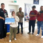 An athlete with unique abilities and members of the seminar 'Way of the Warrior' posing with the donation check