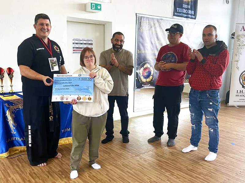 An athlete with unique abilities and members of the seminar 'Way of the Warrior' posing with the donation check
